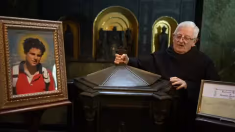 Le père Paul Addison montre les fonts baptismaux où Carlo a été baptisé en 1991.